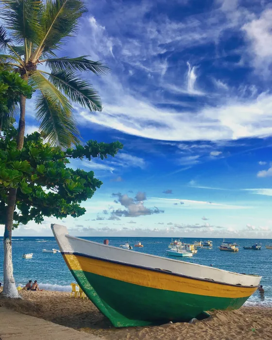 Ein bemaltes Fischerboot am Strand in Bahia, dahinter der Ankerplatz