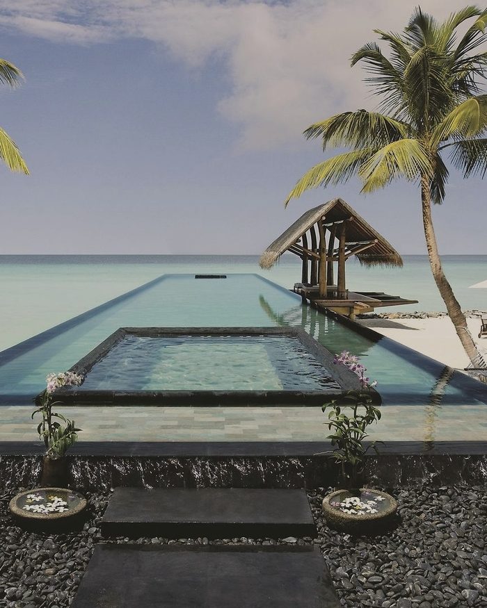 Infinity-Pool mit Pavillon und Palme, dahinter die Lagune